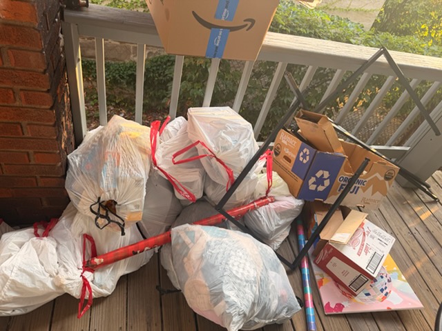 Bagged trash and broken furniture staged on a back deck for pickup