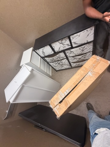 Crew member carrying a headboard out of a bedroom