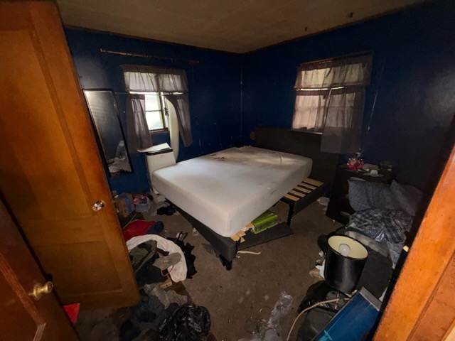 A bedroom part way through a TK Junk Removal cleanout, mattress and clutter still to go